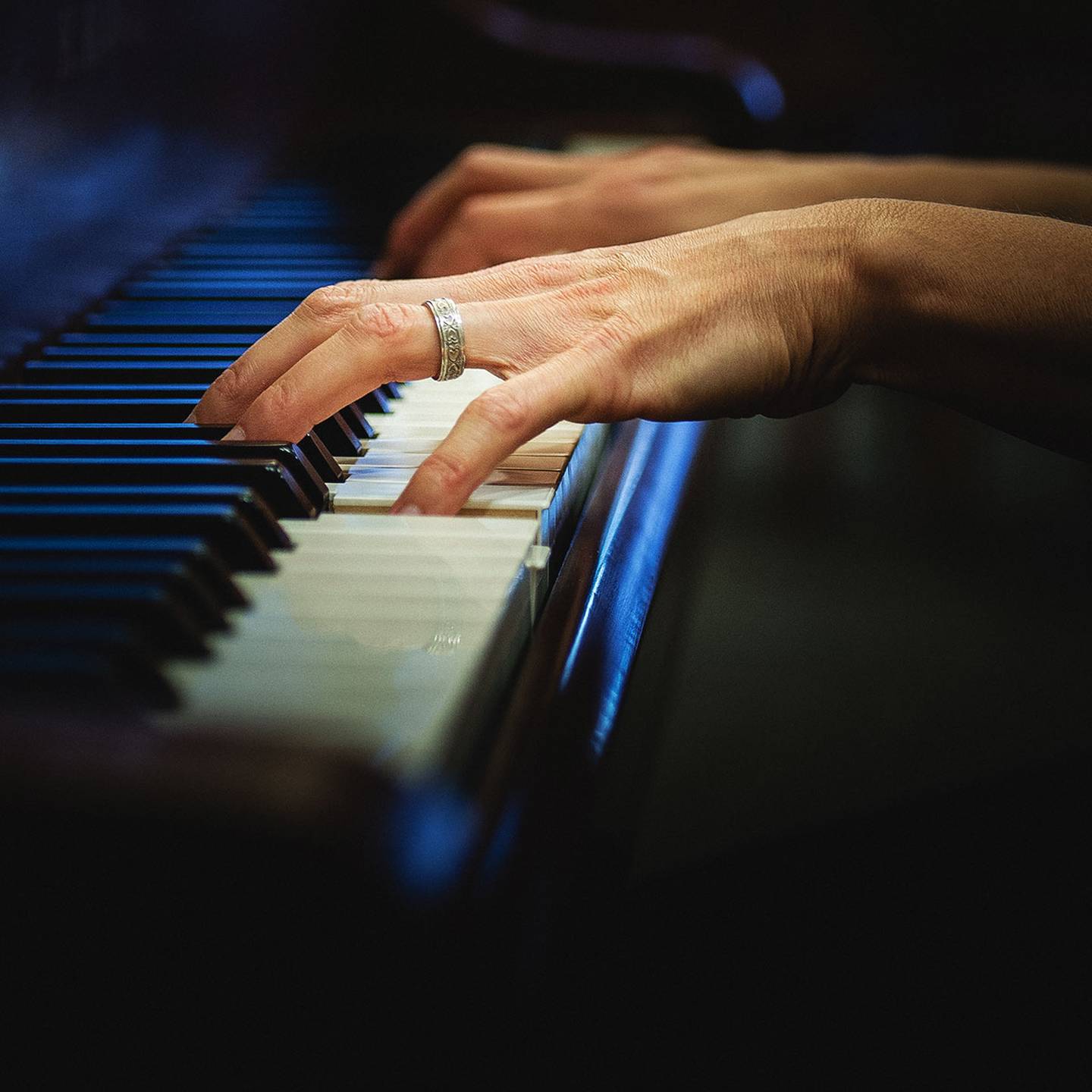 Close up of hands playing a piano.