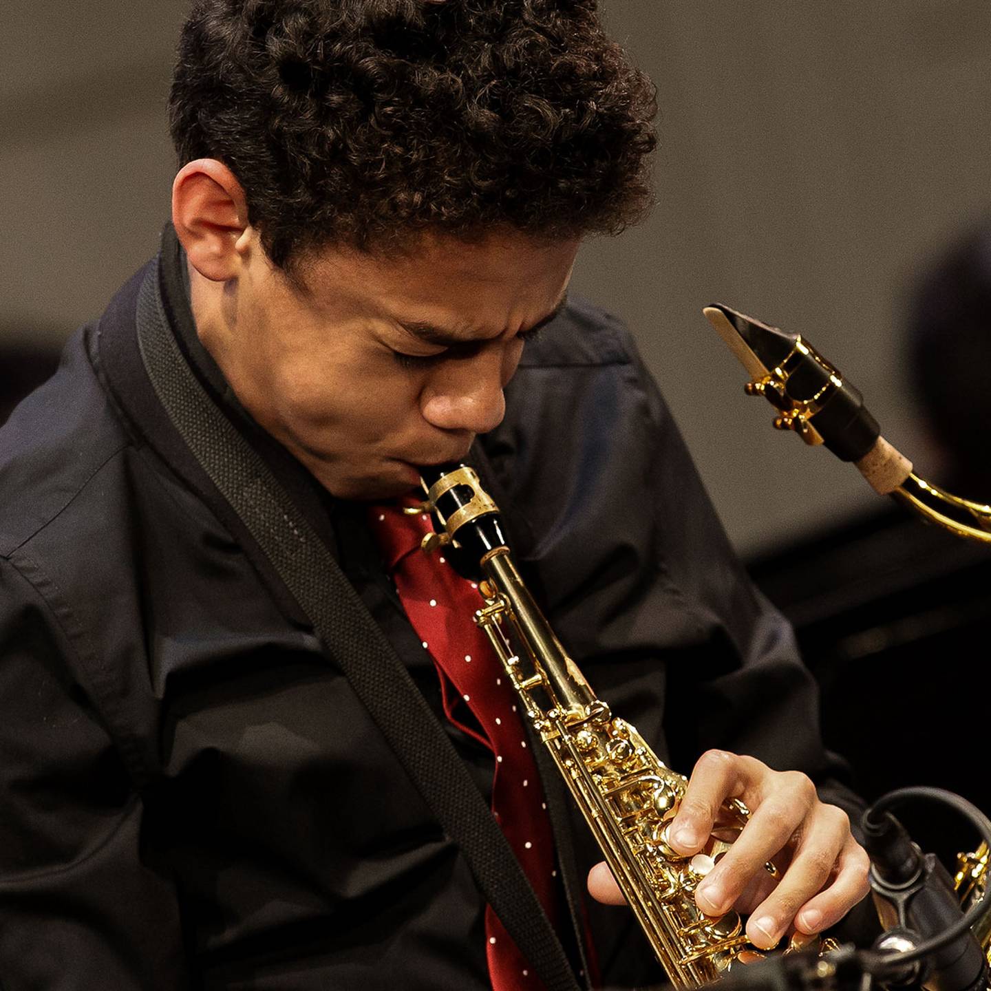 Close up of a man playing a saxaphone in concert.