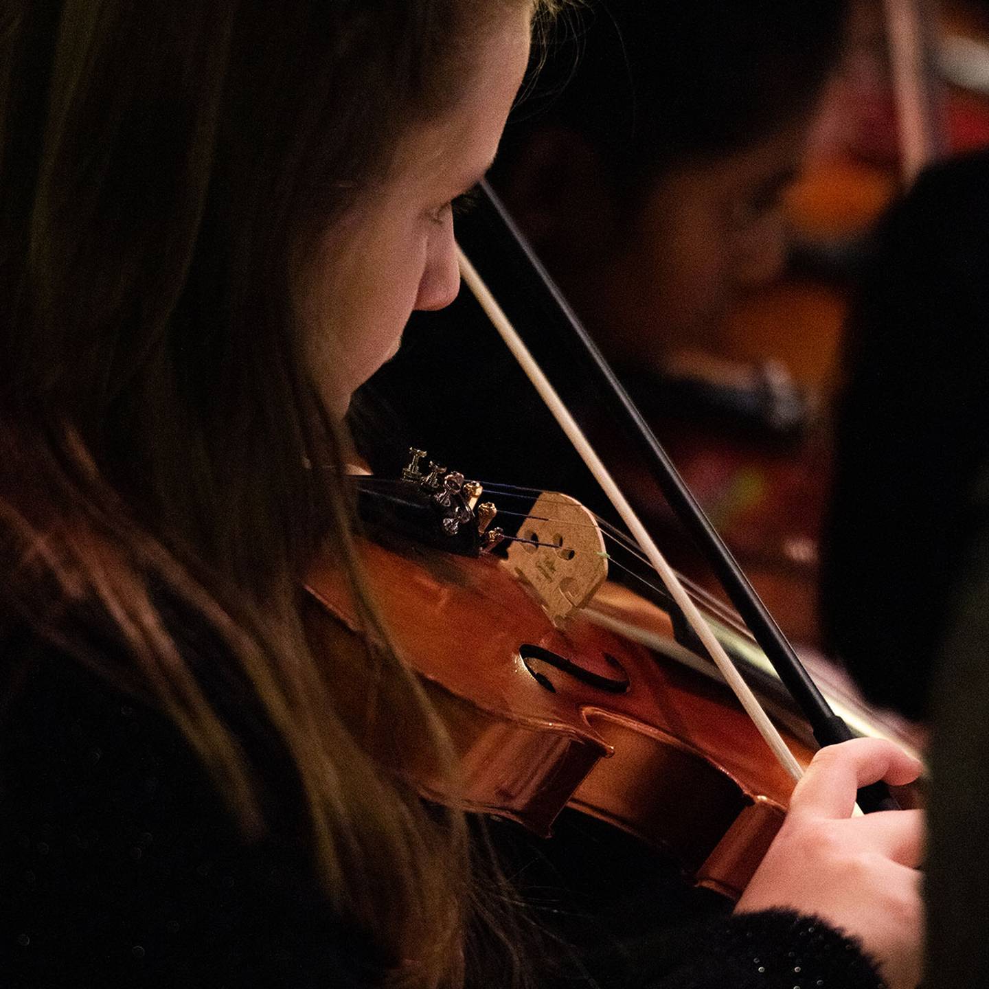 Close up of a woman playing a violin in concert.