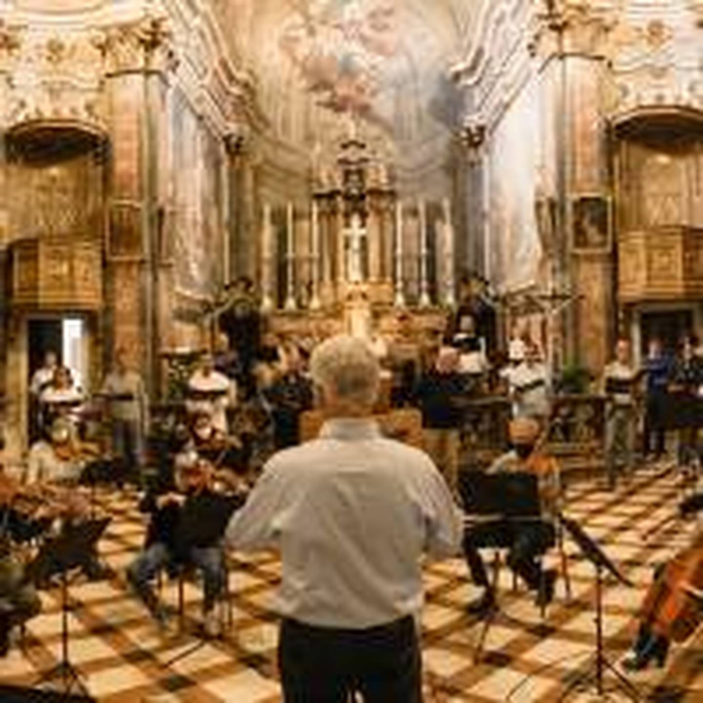 Musicians in chairs inside cathedral playing instruments.
